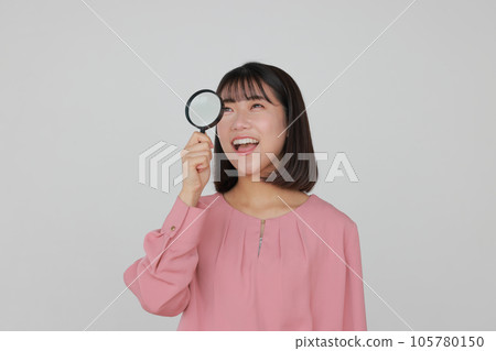 A casually dressed woman looking through a loupe and finding something _1 105780150