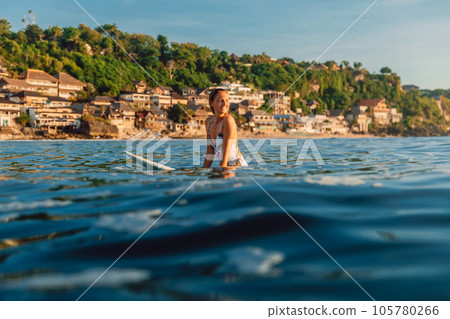Surfer woman sitting on surfboard during surfing in ocean. Surfer woman sitting on surfboard during surfing in ocean. 105780266