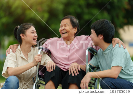 happy grandson and granddaughter talking with senior woman in wheelchair at park 105785039