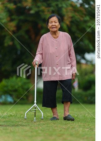 senior woman with walking stick in the grass field at park senior woman with walking stick in the grass field at park 105785041