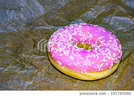A delicious pink donut. Sweet donut with icing and sugar decoration. Object concept. Side view. Lying flat. Food concept. Macro concept. Sugar is bad for health A delicious pink donut. Sweet donut with icing and sugar decoration. Object concept. Side view. Lying flat. Food concept. Macro concept. Sugar is bad for health 105785098