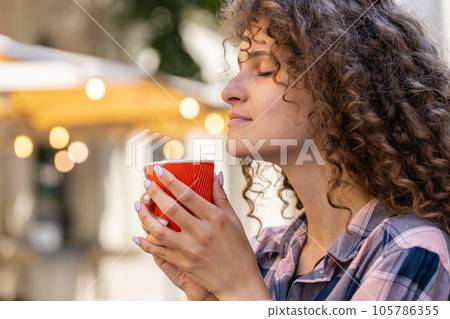 Young woman girl enjoying drinking morning coffee hot drink, relaxing, taking a break in city street Young woman girl enjoying drinking morning coffee hot drink, relaxing, taking a break in city street 105786355