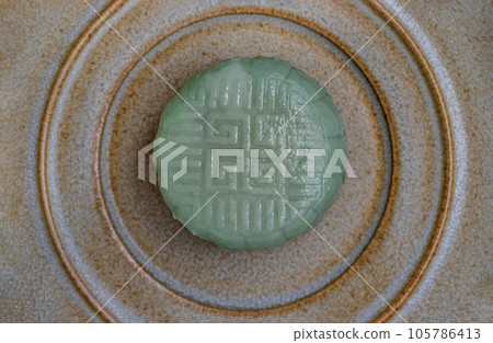 Green mooncake is filled with taro, black sesame and golden thread egg on ceramic plate. 105786413