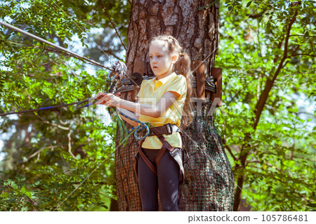 A child in a forest adventure park made of ropes. A child in a forest adventure park made of ropes. 105786481