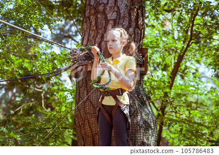 A child in a forest adventure park made of ropes. A child in a forest adventure park made of ropes. 105786483