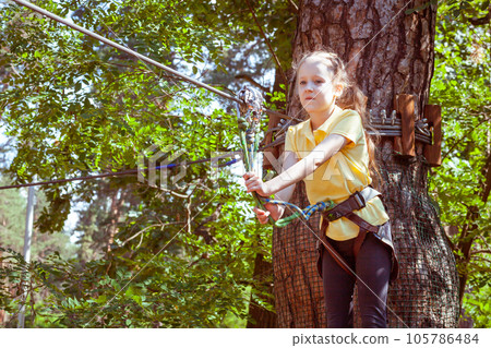 A child in a forest adventure park made of ropes. A child in a forest adventure park made of ropes. 105786484