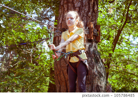 A child in a forest adventure park made of ropes. A child in a forest adventure park made of ropes. 105786485