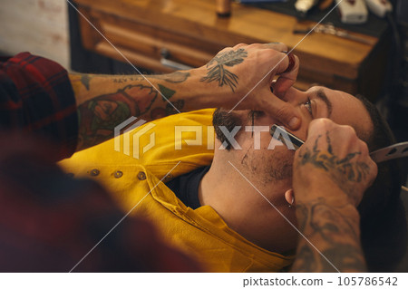 Client during beard shaving in barber shop 105786542