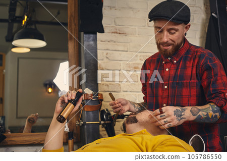 Client during beard shaving in barber shop 105786550