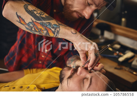 Client during beard shaving in barber shop 105786558