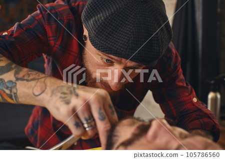 Client during beard shaving in barber shop Client during beard shaving in barber shop 105786560