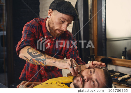 Client during beard shaving in barber shop Client during beard shaving in barber shop 105786565