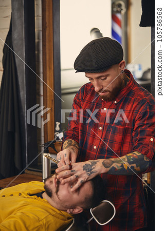 Client during beard shaving in barber shop 105786568