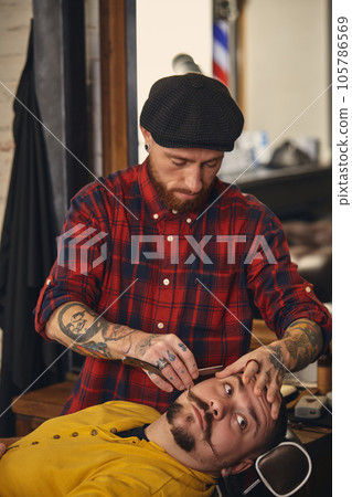 Client during beard shaving in barber shop 105786569