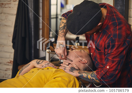 Client during beard shaving in barber shop Client during beard shaving in barber shop 105786579