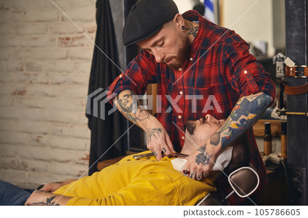 Client during beard shaving in barber shop Client during beard shaving in barber shop 105786605