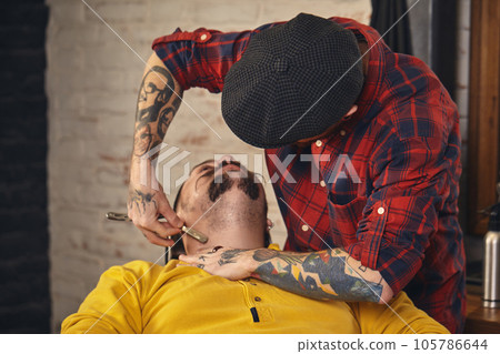 Client during beard shaving in barber shop Client during beard shaving in barber shop 105786644