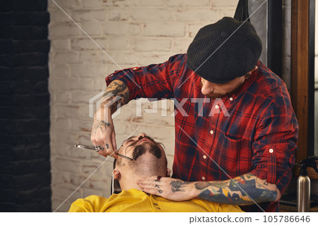 Client during beard shaving in barber shop Client during beard shaving in barber shop 105786646
