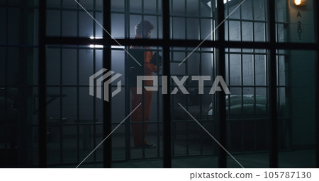Prisoner in orange uniform kneels near bed, prays to God Prisoner in orange uniform kneels near bed, prays to God 105787130