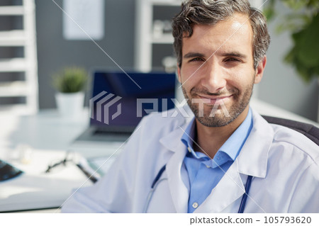 A male doctor in a white coat looks at the medical history and laughs. 105793620