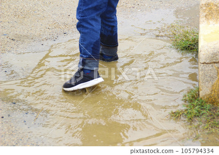 Child playing in puddle (5 years old / boy) 105794334