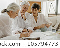 Three mature businesswomen talking and smiling while working in office together. 105794773