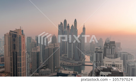 View of various skyscrapers in tallest recidential block in Dubai Marina aerial night to day timelapse 105797024