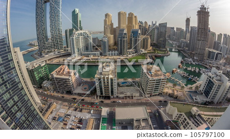 Dubai Marina with several boats and yachts parked in harbor and skyscrapers around canal aerial morning timelapse. 105797100