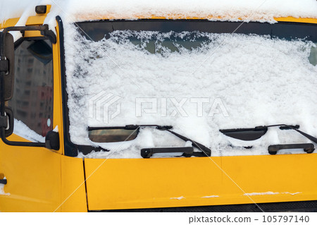 Snow on the windshield of a yellow truck 105797140