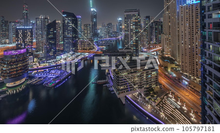 Aerial view to Dubai marina skyscrapers around canal with floating boats night timelapse Aerial view to Dubai marina skyscrapers around canal with floating boats night timelapse 105797181