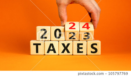 2024 taxes new year symbol. Businessman turns a wooden cube and changes words Taxes 2023 to Taxes 2024. Beautiful orange table orange background, copy space. Business 2024 taxes new year concept. 105797769