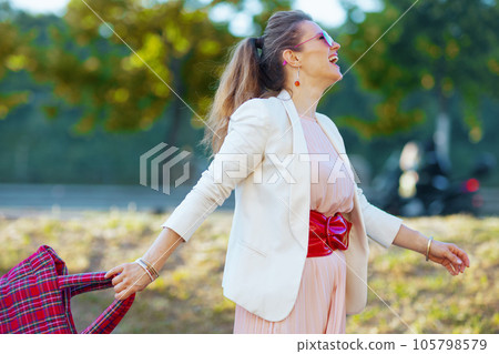 happy trendy woman in dress and jacket in city walking 105798579