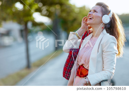 happy stylish woman in city listening to music with headphones happy stylish woman in city listening to music with headphones 105798610