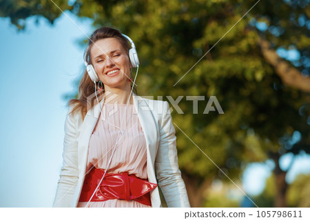 smiling young woman in pink dress and white jacket in city smiling young woman in pink dress and white jacket in city 105798611