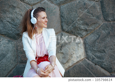 smiling trendy female in city listening to music 105798614