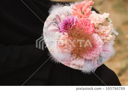 The bride holds her wedding bouquet with red peonies and sunflowers in her hands 105798789