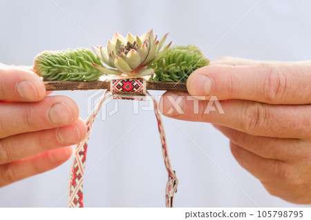 Close-up of hands holding a bow tie with decorative flowers on it 105798795