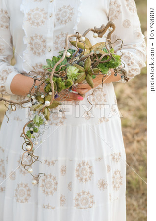 The bride holds an unusual braided wedding bouquet in her hands The bride holds an unusual braided wedding bouquet in her hands 105798802