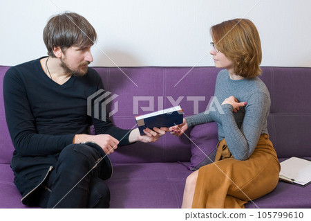 A man with a book in his hands and a psychologist in his office. Social issues, healthcare concept 105799610