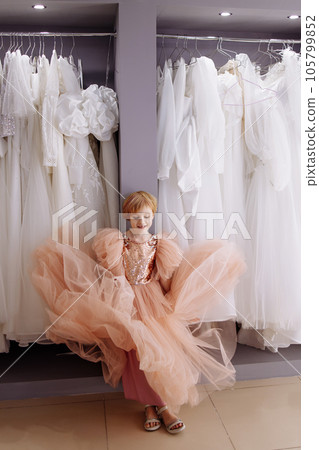 White wedding dresses on hangers in a bridal salon. The girl chooses. 105799852