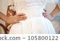 bride fees. the bride is dressed for the wedding. close-up of the bride's hands with a gentle manicure, against the background of a white lace dress . Wedding dress details, close up. 105800122
