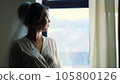 portrait of a bride, beautiful girl, in veil and white peignoir, robe, looks out the window 105800126