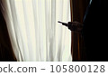 at dusk, in the darkness, opposite the window. handsome man, businessman in a white shirt and blue jacket is holding a smartphone, talking on mobile phone, at home, in his bedroom 105800128