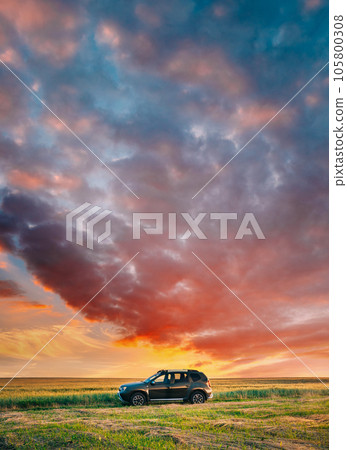 AWD 4WD SUV green car in summer meadow landscape in summer field countryside landscape. Sunset sky background AWD 4WD SUV green car in summer meadow landscape in summer field countryside landscape. Sunset sky background 105800308