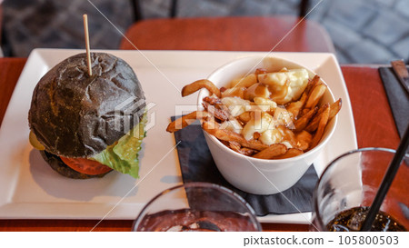 Vegan burger with French fries. Burger with plant based meat cheese. Lunch is on the table. Close-up of a hamburger with cheese on a board.Classic burger. Food day. 105800503