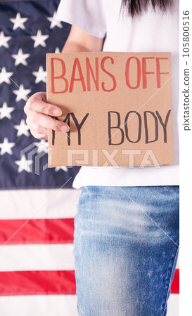 Woman holding a sign Bans Off My Body American flag on background. Protest against anti abortion law. Women's strike. Womens rights freedom. 105800516