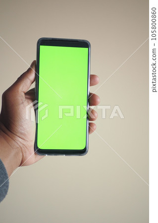 Close up of young man hand using smart phone with green screen  105800860