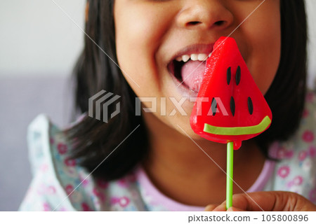 child is licking colorful candy on stick, child is licking colorful candy on stick, 105800896