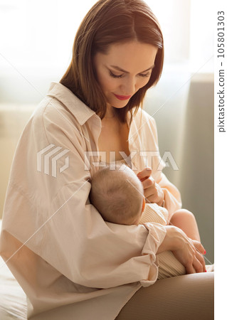 Mother breastfeeding baby daughter in empty bedroom Mother breastfeeding baby daughter in empty bedroom 105801303