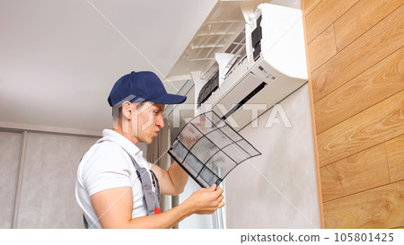 Male service worker finds dust on air conditioner in premise 105801425